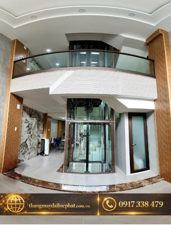 Thang máy kính đặt giữa cầu thang bộ nhìn từ mặt trước